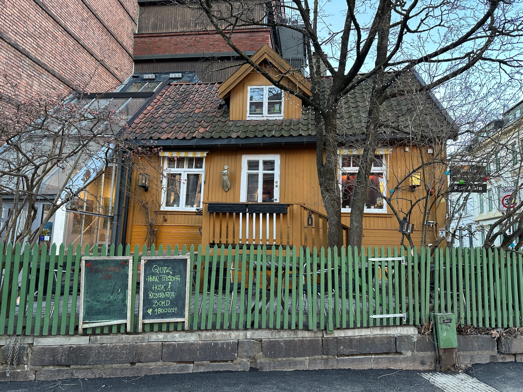 Det gule huset sett utenfra med grønt stakittgjerde
